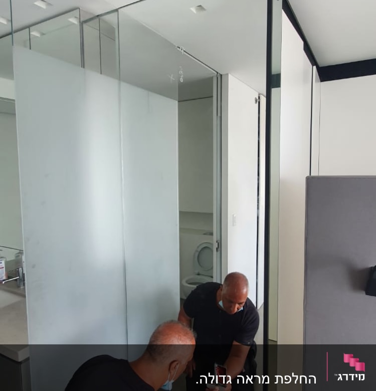 שני אנשים עובדים על התקנת דלת זכוכית